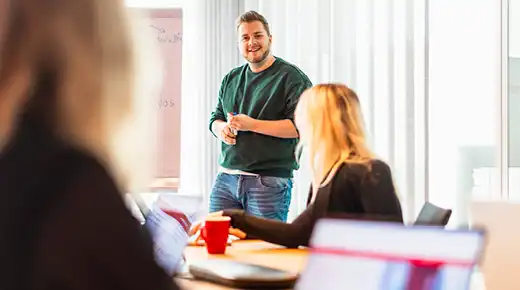 Mann stellt Kollegen etwas am Whiteboard vor