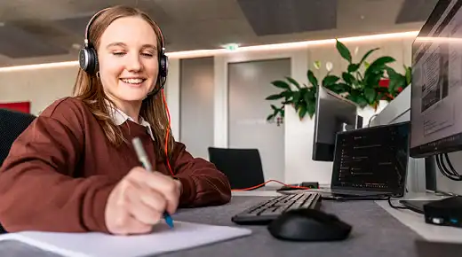 Frau mit Kopfhörern macht sich Notizen