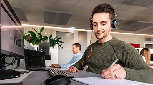 Mann mit Kopfhörern macht sich Notizen