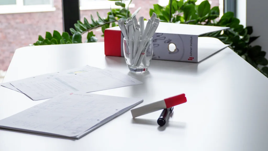 Documents, a binder and Johner pens on a meeting table at the Johner Institut.