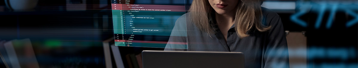 Frau sitzt vor ihrem Laptop und programmiert