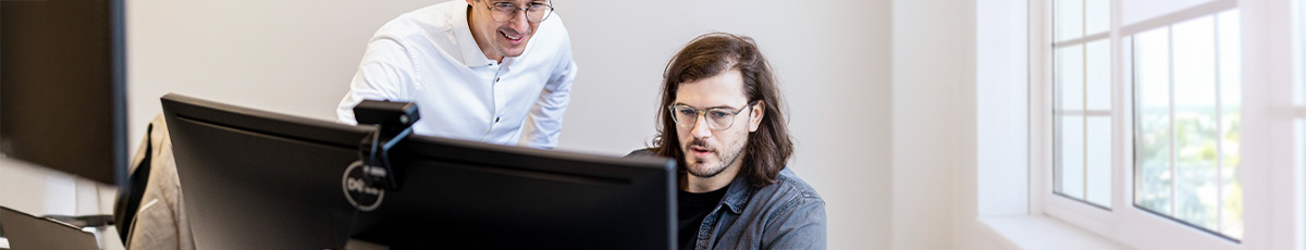 Mann hilft einem anderen beim Arbeiten am Computer