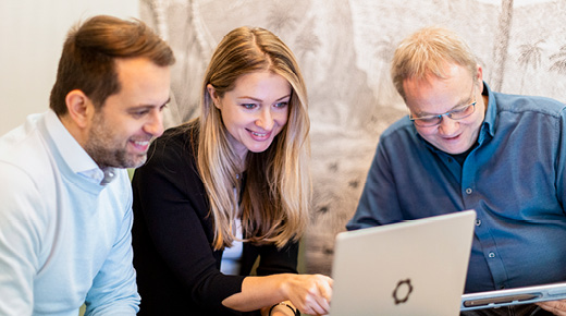Drei Kolleg:innen analysieren etwas am Laptop