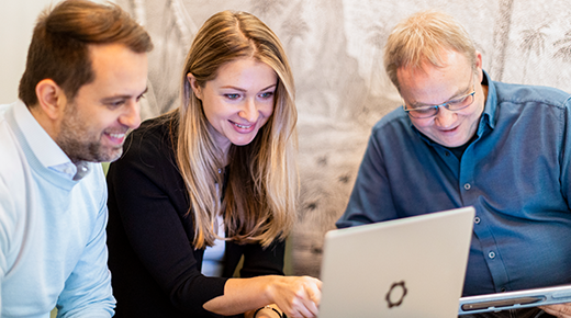 Drei Kolleg:innen analysieren etwas am Laptop