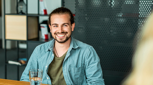 Lächelnder Mann im Gespräch mit Kollegin