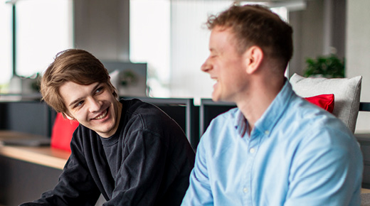 Zwei Kollegen im Büro unterhalten sich und lachen
