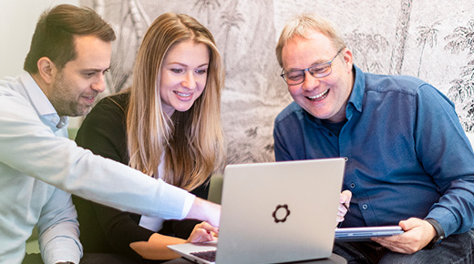 Mann zeigt zwei Kolleg:innen etwas am Laptop