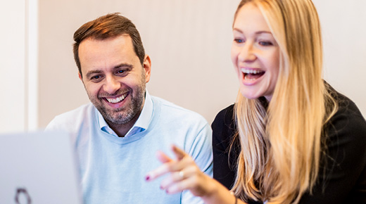 Mann und Frau schauen etwas am Laptop an und lachen dabei