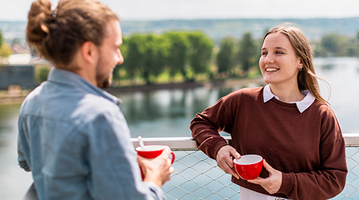 Zwei Mitarbeitende trinken Kaffee auf der Terrasse